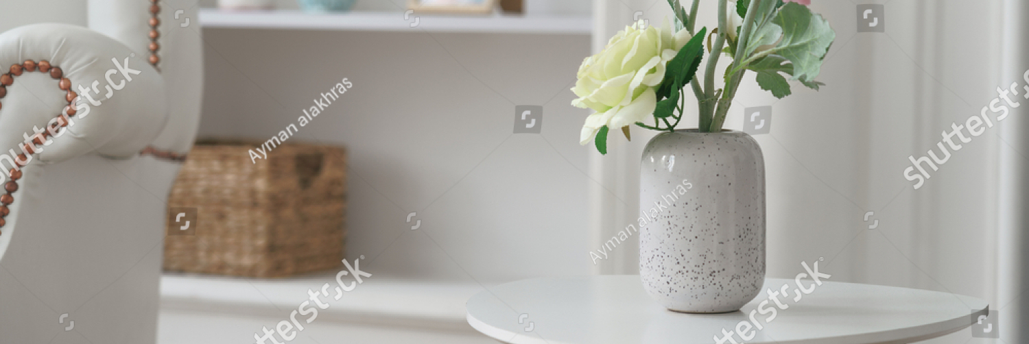 stock photo pink and yellow roses in modern white vase on white table beside classic armchair 1775289059