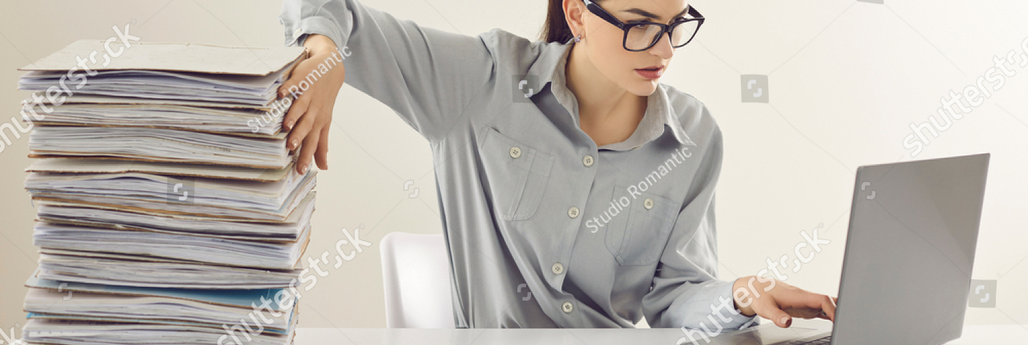 stock photo young accountant working on laptop computer sitting at desk with pile of papers paperwork vs 1916116798